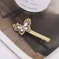Elegant gold butterfly hair clip with pink crystals and rhinestones on a magazine - Butterfly Style