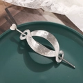 Macro detail of silver geometric oval hair clip and heart pin on dark green tray - Heart Decor Silver