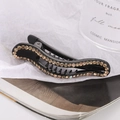 Close-up of black hair clip with amber rhinestones and anti-slip teeth on magazine - Champagne
