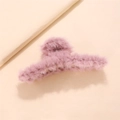 Close-up of a large pale pink plush hair claw clip with soft faux fur on a beige stand - Purple