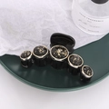 Elegant black hair claw clip with five gold foil button accents on a ceramic plate - Black base Black