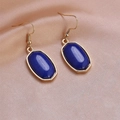 Detail of elongated hexagon earrings with blue stone and gold hooks on champagne silk - Sapphire Blue