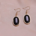 Elegant gold-rimmed earrings with black marble stones on a soft pink silk background - Black