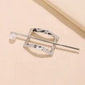 Dettaglio di forcina in metallo argentato ondulato con perla lucida su sfondo minimalista - Stile Perla Rettangolare Argento