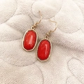 Elegant gold drop earrings with oval red stones on a soft textured grey background - Burgundy