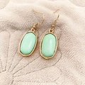 Minimalist mint green octagonal drop earrings with golden metal trim on grey fur - Fruit Green
