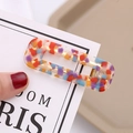 Macro shot of rectangular acetate hair clip with colorful mosaic pattern and gold metal base - Multicolor