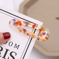 Close-up of a colorful terrazzo-style acrylic hair clip with gold metal duckbill clip - Transparent Red Multi
