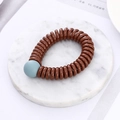 Brown spiral telephone wire hair tie with a light blue bead on marble background - Coffee (D6116)