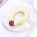 Detail of a creamy white spiral hair tie with a matte red bead on a marble tray - Beige (D6117)