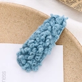 Dettaglio di un fermaglio per capelli blu in lana riccia su un vassoio elegante - Celeste (E6210)