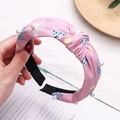 Detalle de diadema rosa con flores, perlas blancas y diseño de nudo central moderno - Rosa