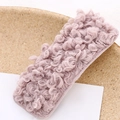 Gros plan d'une barrette rectangulaire en peluche bouclée rose-violet sur bois - Rose Lotus