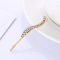 Elegant gold-plated hair clip with sparkling transparent crystals on a white ceramic dish - Wavy (B6123) / Gold