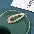 Detailed close-up of golden hammered metal teardrop hair clip in a green ceramic tray - Large Hollow Waterdrop Style (C2237) / Gold