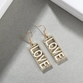 Detaillierte Makroansicht vergoldeter rechteckiger Ohrringe mit Strassstein LOVE Schriftzug - LOVE Gold + Weiß