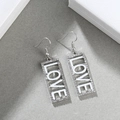 Detaillierte Nahaufnahme silberner LOVE-Ohrhänger mit funkelnder Strass-Dekoration für Damen - LOVE Silber + Weiß
