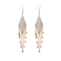 Détail de longues boucles d'oreilles dorées à pampilles et strass sur fond blanc - Or