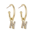 Detail of gold letter N earrings featuring sparkling pave set rhinestones on white backdrop - Gold N