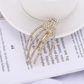 Detailed macro view of gold skeleton hand hair clip with sparkling inlaid rhinestones - White (C3201)