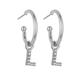 Macro detail of silver hoop earrings featuring sparkling diamond-encrusted letter L pendants - Silver L