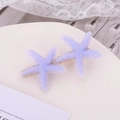 Macro shot of purple beaded starfish hair clip on elegant white display stand - Purple