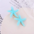 Close-up of blue starfish hair clips with frosted texture on a white decorative tray - Blue