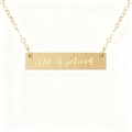 Macro shot of gold horizontal bar necklace engraved with Love is patient quote - Love is Patient Style