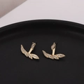 Elegant gold-tone irregular leaf earrings with sparkling white rhinestones on black tray - Gold