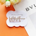 Goldene Haarklammer mit LOVE-Schriftzug und funkelnden Straßsteinen auf Display-Karte - Roségold LOVE Stil