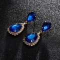 Makro-Detail von eleganten blauen Zirkonia-Ohrhängern in Tropfenform mit Vergoldung - Gold Königsblau