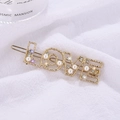 Detailaufnahme der goldenen LOVE-Haarklammer mit Perlen und funkelnden Steinen - Love Stil / Gold