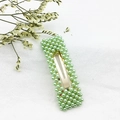 Dettaglio di un fermaglio per capelli in metallo dorato con perle verde chiaro su fondo bianco - Quadrato Verde (C2333)