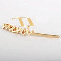 Minimalist golden alloy hair clip featuring a cursive Merci letter design for women - Gold Merci