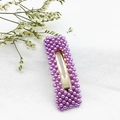 Gros plan détaillé d'une pince à cheveux dorée aux perles violettes sur tissu blanc - Carré Violet (C2333)