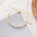 Detail view of a cat-shaped golden metal hair clip with a polished finish on grey paper - Gold