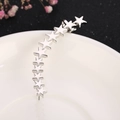 Detalle del pendiente tipo ear cuff plateado con once estrellas pulidas en un plato blanco - Estilo Estrella (Derecha)