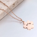 Detalle del collar con colgante de pata en oro rosa sobre fondo de piedra beige - Oro rosa