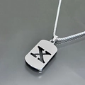 Vue macro d'un collier pendentif lettre X argenté ajouré sur une surface réfléchissante - Style Lettre X