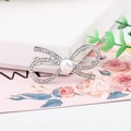 Close-up of silver bow hair clip with white pearls and rhinestones on a spring clip - Thick Silver / Style Twelve (B8102)