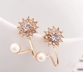 Vue macro d'une boucle d'oreille fleur avec strass et perle blanche sur porcelaine blanche - Doré