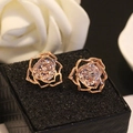 Close-up of rose gold hollow rose earrings with a sparkling zircon center on a black box - Rose Gold
