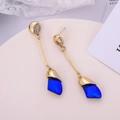 Detailed view of long gold drop earrings featuring a faceted dark blue crystal gem pendant - Blue