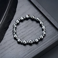 Bracelet en hématite gris foncé avec perles à facettes sur un plateau en bois noir - Style Rond Facetté (S733-C)