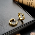 Vintage gold hoop earrings with embossed texture on black leather and scroll background - Antique Gold