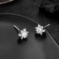 Makroaufnahme von silbernen Schneeflocken-Ohrringen mit Zirkonia auf dunklem Tablett - Silber