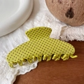 Detailed view of a green polka dot hair claw clip on a white lace fabric background - Emerald Green with Polka Dot