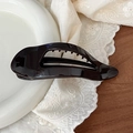 Detail view of a 11.5cm glossy black hair claw clip on elegant lace and ceramic plate - Coffee