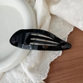 Detail of the glossy black hollow drop-shaped hair claw clip on a white ceramic tray - Glossy Black