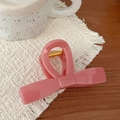 Pink bow-shaped hair claw clip in smooth acrylic on a woven mat with cozy home decor - Bow Knot Bar (Plum Pink)